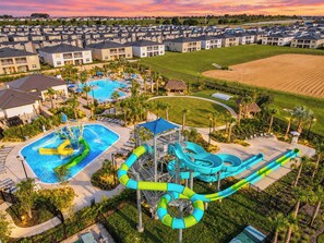 A resort with a swimming pool, water slides, and a large lawn area.