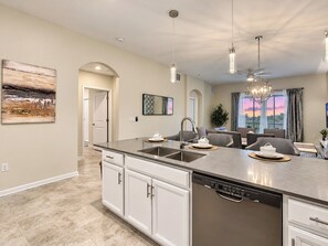 A modern kitchen with a central island, stainless steel appliances, and pendant lighting.