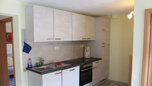 A compact kitchen with a sink, stove, and cabinets.