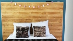 A bedroom with a wooden headboard, a bed with two pillows, a fluffy rug, and a wall-mounted picture. - Pleasant country cottage in a quiet location (Wirwignes)