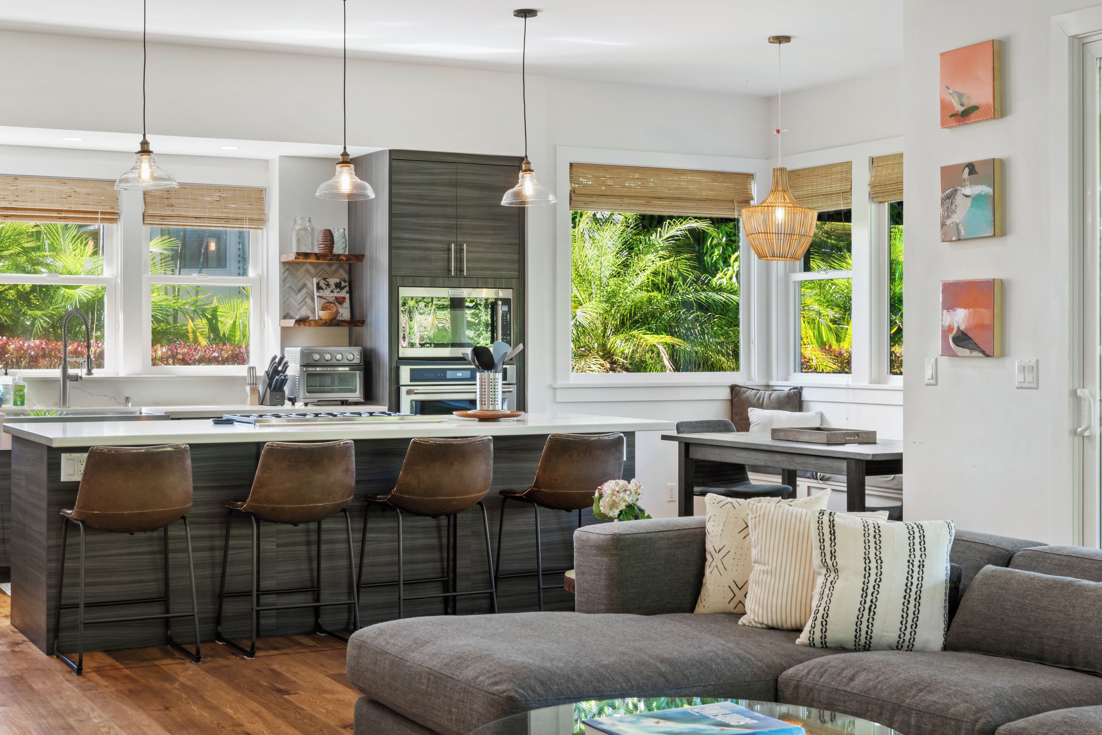 A modern kitchen with a central island, bar stools, and pendant lighting.