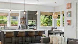 Een moderne keuken met een centraal eiland, barstoelen en hanglampen.