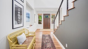 Een modern interieur met een trap, kunstwerken in lijsten en een rieten bank.
