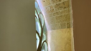 A narrow hallway with a decorative glass window and a brick wall. - Abitazione Tipica (Lecce)
