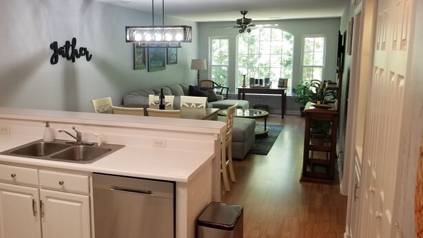 A modern kitchen with white cabinetry, a double sink, and a dining area with a table and chairs. - Beautiful, 3 br/2 bath condo in Pawleys Island, SC. Minutes from the beach. (Pawleys Island)