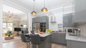 A modern kitchen with grey cabinets, a central island, and pendant lighting. - Summer Salt – St Ives – Sleeps 4 – Parking – Outside Space (St Ives)