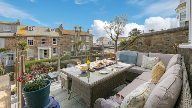 A terrace with a wicker table set for dining, a sofa, and a potted plant. - Summer Salt – St Ives – Sleeps 4 – Parking – Outside Space (St Ives)