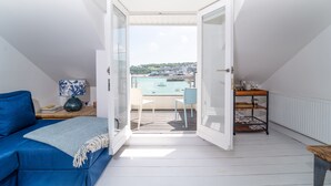 Un balcón con vistas al puerto, un sofá azul y una mesa con lámpara.