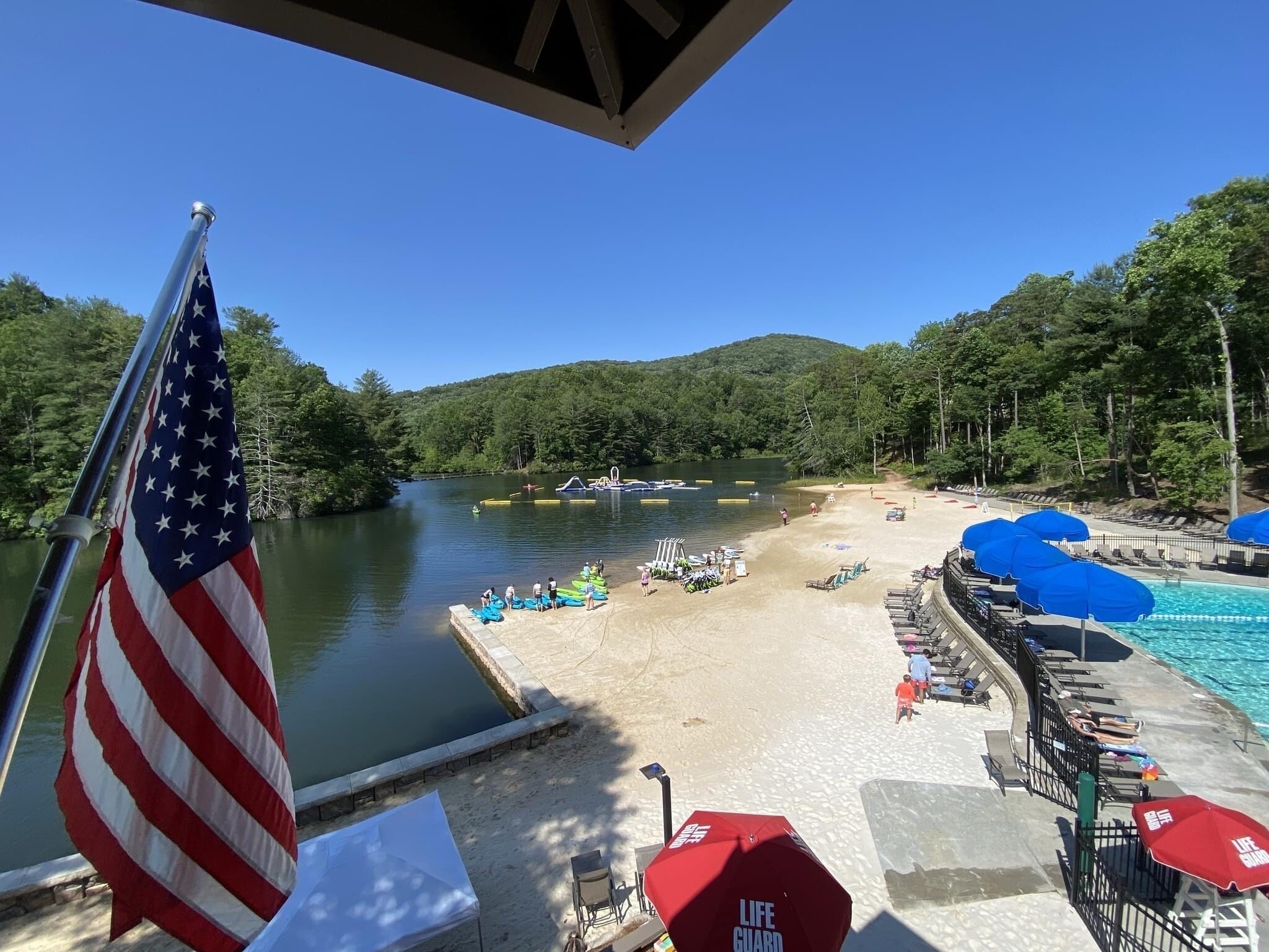 Une zone de baignade au bord du lac, avec un quai, des bateaux et un poste de surveillance des sauveteurs.