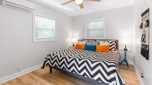 A bedroom with a bed, ceiling fan, two bedside lamps, and a wall-mounted tapestry. - Experience the Vibrant Downtown St Pete! (St. Petersburg)