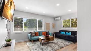 A modern living room with a light wood floor, two sofas, a coffee table, and a TV mounted on the wall. - Experience the Vibrant Downtown St Pete! (St. Petersburg)