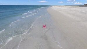 A beach with a chair on the sand. - Experience the Vibrant Downtown St Pete! (St. Petersburg)
