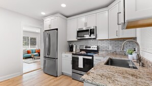 A modern kitchen with white cabinets, stainless steel appliances, and a granite countertop. - Experience the Vibrant Downtown St Pete! (St. Petersburg)