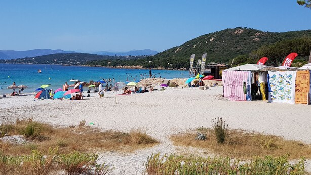 A beach with tents and umbrellas, a clear sky, and a hilly landscape in the background. - Porticcio, Superb air-conditioned T2, panoramic view of the Gulf of Ajaccio (Albitreccia)