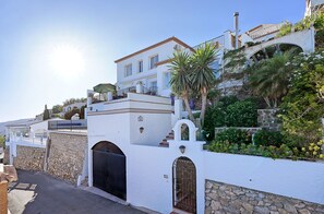 A white building with a stone wall, a black gate, and a staircase leading to a balcony. - 🏝Villa Calypso, private pool, 180º ocean view☀️ (Salobreña)