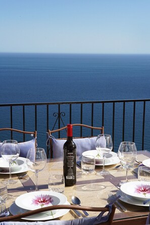 A table set for dining with a bottle of wine, plates, and glasses, overlooking a body of water. - 🏝Villa Calypso, private pool, 180º ocean view☀️ (Salobreña)