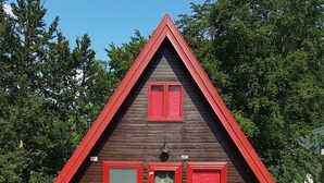 A triangular wooden cabin with a red roof, a green door, and two red windows. - Gemütliches Ferienhaus am Twistesee im Ferienland Waldeck-frankenberg (Bad Arolsen-Wetterburg)