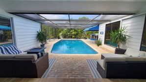 Une piscine extérieure couverte, avec des espaces de détente adjacents et des plantes en pot.