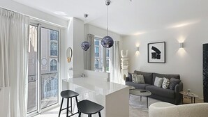 Un salon moderne comprenant un canapé, une table basse, un coin bar avec des tabourets et un grand miroir.