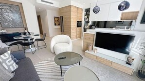 Un salon moderne comprenant un canapé, une table basse, un téléviseur et un coin repas.