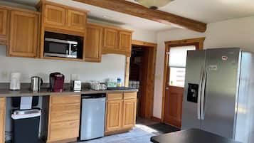 A kitchen with wooden cabinets, a stainless steel refrigerator, a microwave, a coffee maker, and a dishwasher.