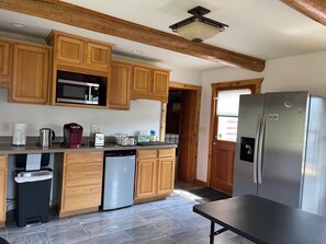 A kitchen with wooden cabinets, a stainless steel refrigerator, a microwave, a coffee maker, and a dishwasher.