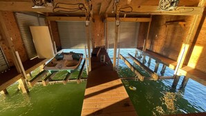 Ein Blick ins Innere einer Holzhütte, mit einem Steg, der sich über das Wasser erstreckt.