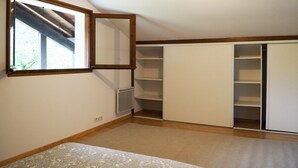 Ein Schlafzimmer mit großem Fenster, eingebautem Kleiderschrank und Heizkörper.