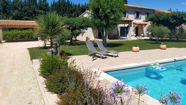 A poolside area with lounge chairs, a swimming pool, and a house with a tiled roof. - Lou Mazet provençal à Eygalières - Private swimming pool (EYGALIERES)