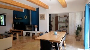 A modern living room with a wooden dining table, black chairs, a TV, and a fireplace. - Lou Mazet provençal à Eygalières - Private swimming pool (EYGALIERES)