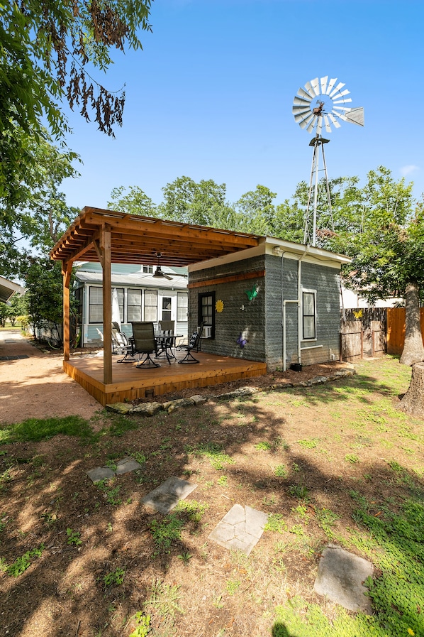 Uma casa com alpendre, um moinho de vento e um quintal com caminho de pedra.
