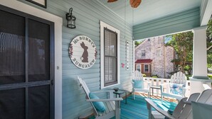 A porch with white Adirondack chairs, a table, and a sign reading "Ms. Bunny's Bungalow." - .6 miles to Marktplatz - Walkable to Downtown - Firepit - (Fredericksburg)