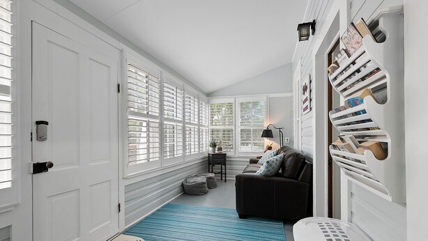 A hallway with a blue striped rug, a white trash bin, and a black sofa with patterned cushions. - .6 miles to Marktplatz - Walkable to Downtown - Firepit - (Fredericksburg)
