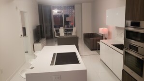 Una cocina moderna con armarios blancos, un comedor con mesa blanca y un sofá.