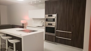 Una cocina moderna con una isla central, horno empotrado y un armario de madera.