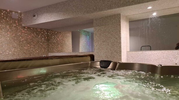 Uma área de hidromassagem com paredes revestidas de azulejos e um banco.