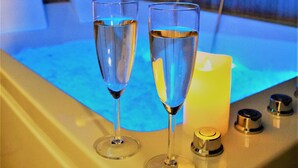 Un'ambientazione da spa con due bicchieri di champagne e una candela su una superficie riscaldata.