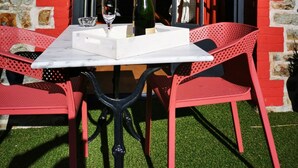 Un tavolo apparecchiato con una bottiglia di champagne, bicchieri e un vassoio bianco, di fronte a un edificio con pareti in mattoni rossi e una facciata in pietra.