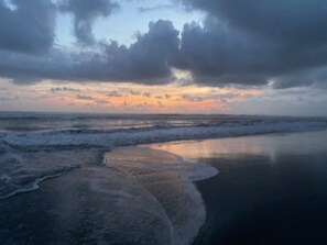 Une plage avec des vagues et un ciel nuageux.