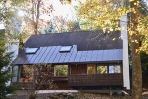 Une maison moderne avec un toit en pente, de grandes fenêtres et une terrasse en bois.