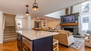 A spacious living area with a large island, a fireplace, and a view of the outdoors. - 2026 Seasonal Summer Rental (Winhall)