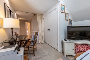 Un espace de vie compact comprenant une table à manger en verre, un canapé, un téléviseur et une imprimante.