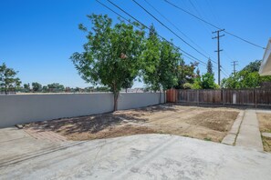Relax in the serene backyard, surrounded by a mature tree and a patio area.