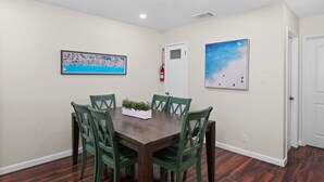 A dining area with a rectangular table, six chairs, and two wall-mounted paintings.