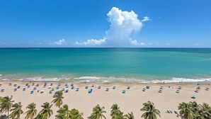Een strand met tal van parasols en palmbomen.