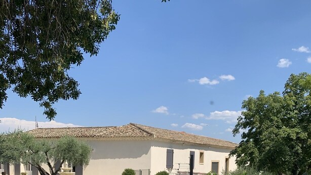 Ein Poolbereich mit Liegestühlen und einer Fontäne, umgeben von einem Gebäude mit einem Ziegeldach.