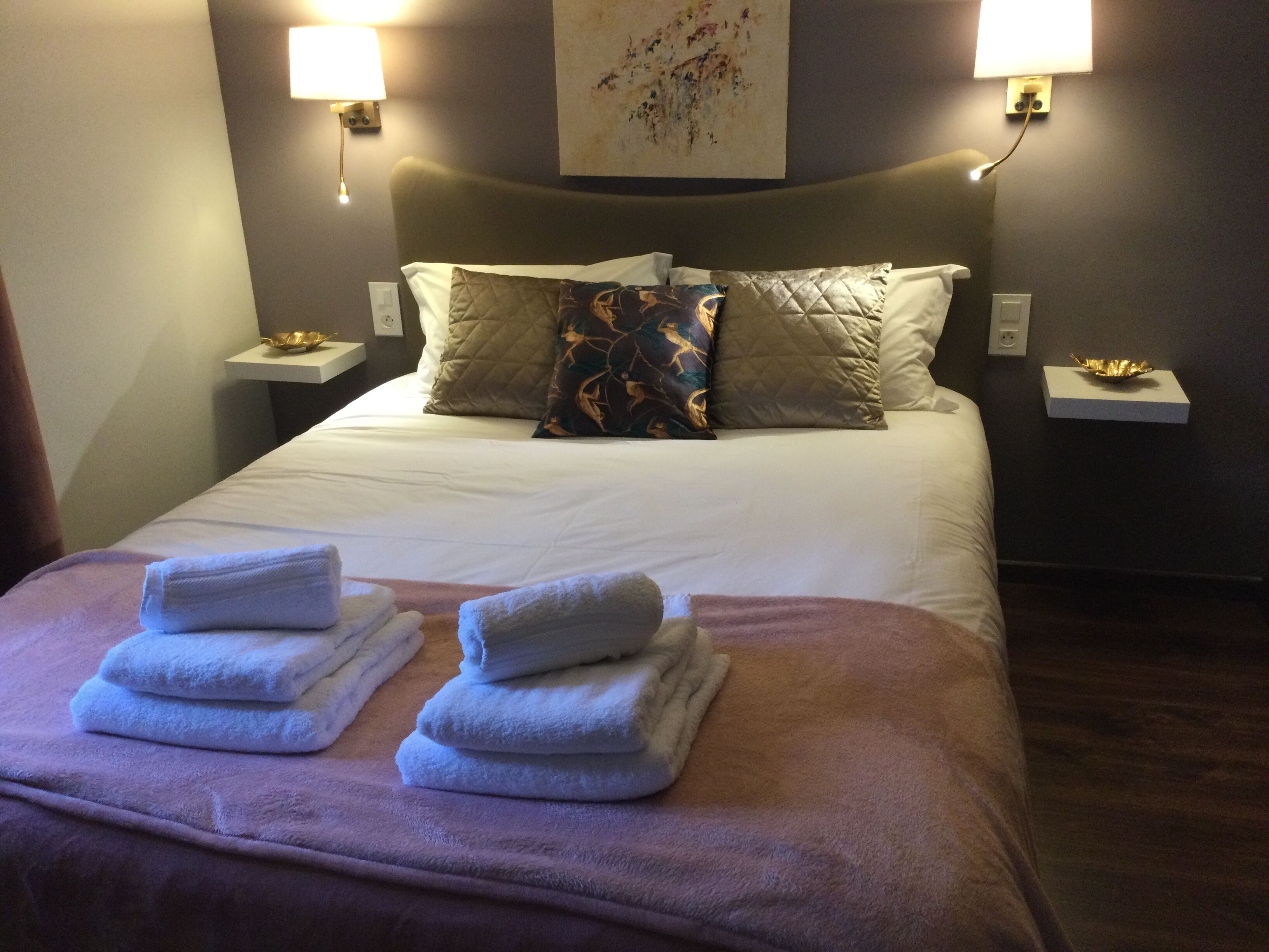 A hotel room with a neatly made bed, two bedside tables with lamps, and a wall-mounted artwork.