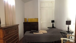 Ein Schlafzimmer mit Bett, Kommode, Nachttischen und einer Tür.