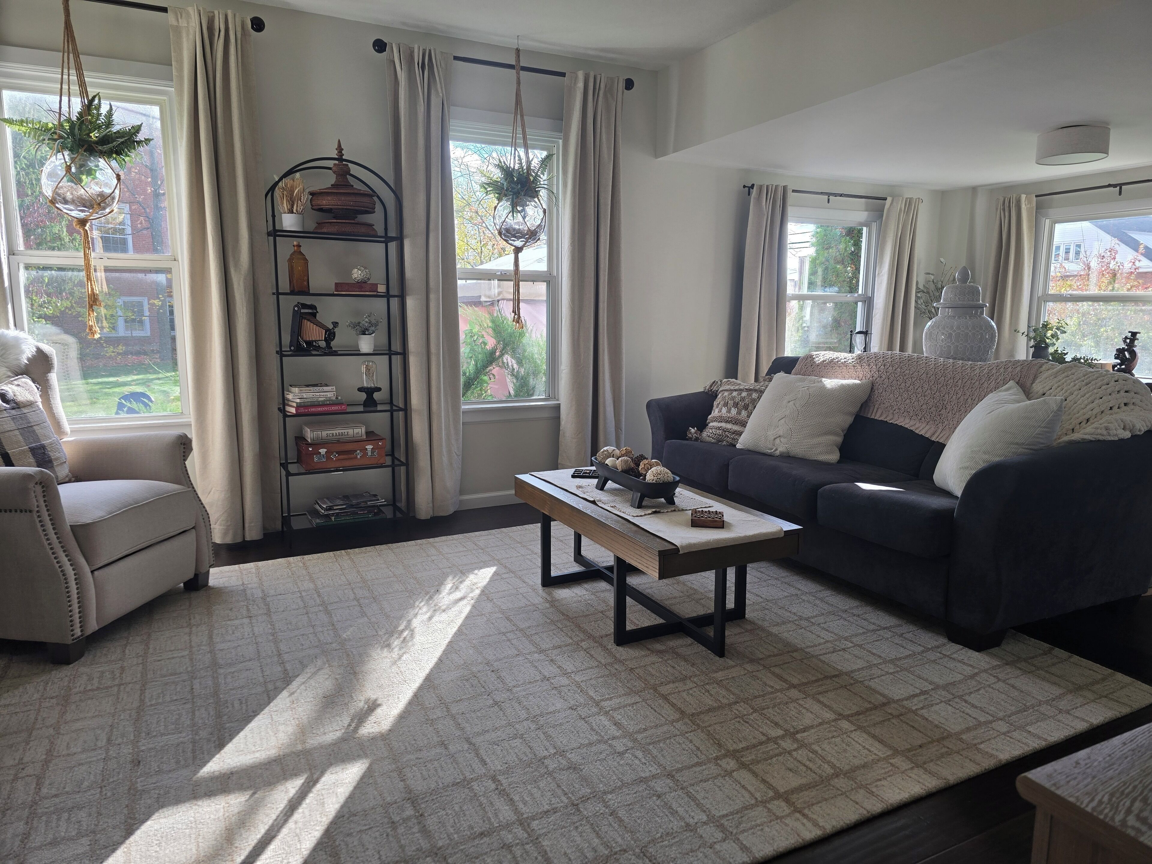 Een woonkamer met een bank, fauteuil, bijzettafeltje en een boekenkast.