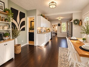 Une cuisine moderne avec un plancher en bois foncé, des meubles blancs et un îlot central.
